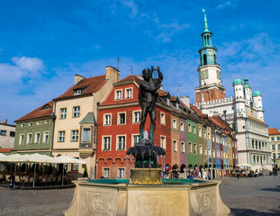 Unidentified people walk past colourful traditional buildings and the Town Hall of Stary Rynek Square in Poznan, Poland