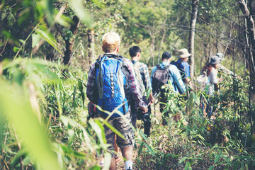Naklejka na ściany i meble Close up of friends walking with backpacks in woods from back.