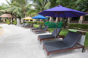 Beach sofa with umbrella beside swimming pool