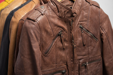 Different color leather jacket hanging on rack on white background