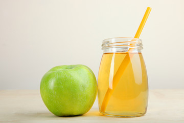 Apple juice in a glass stands on a neutral background
