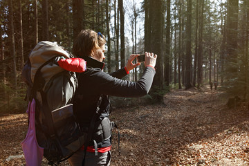 Hiker taking photographs on her hike through the woods