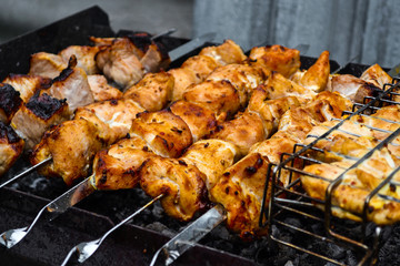 Grilled kebab cooking on metal skewer closeup. Roasted meat cooked at barbecue. Traditional eastern dish, shish kebab. Grill on charcoal and flame, picnic