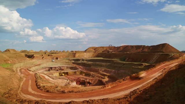 Time lapse of open-cast. Operating mine. Bauxite quarry. Excavators load ore into dump-trucks. This area has been mined for buaxite, aluminum and other minerals.