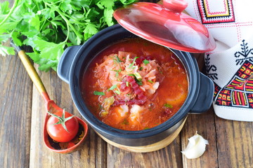 Fasting food. Vegetable soup with sauerkraut, beetroot, carrots, onions, tomato in a black pot on a wooden background. Traditional Eastern European food. Healthy eating concept