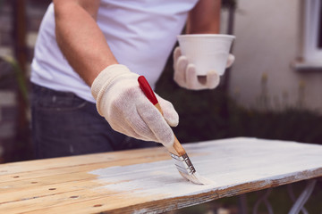Man hand with paintbrush painting on a wooden table