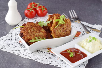 Fried egg plant fritters with tomato and yogurt sauce in a white bowl on a grey abstract background. Healthy food. Healthy breakfast