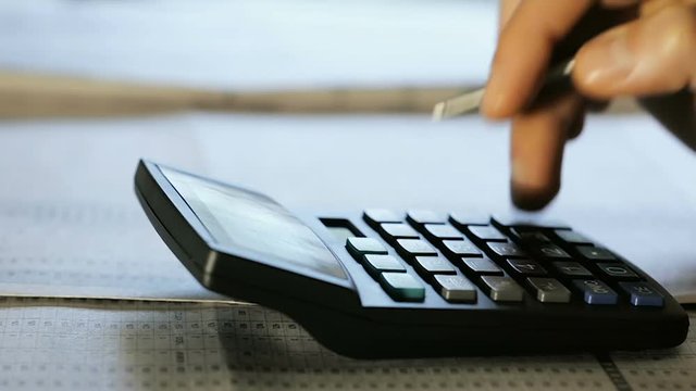 Close-Up Accountant Counts the Balance on a Calculator