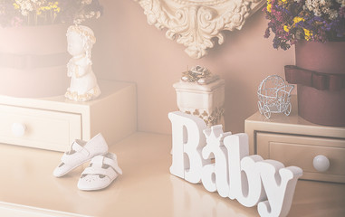 Wooden word "baby" near children's shoes on the table