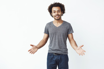 Stylish and handsome african man with arms wide open against white wall inviting to a gig.
