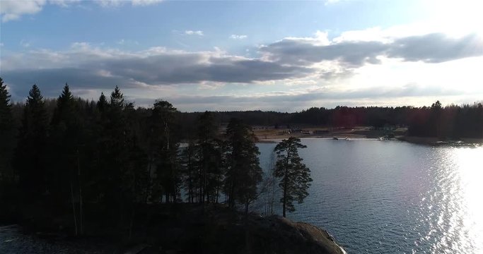 Oittaa, Cinema 4k aerial rising view behind trees revealing Oittaa beach, at bodom lake, on a sunny spring day, in Espoo, Finland