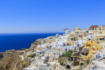 Fototapeta na wymiar Picturesque view of Old Town Oia on the island Santorini, white houses, windmills and church with blue domes, Greece