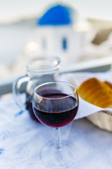 Red greek wine and picturesque view of Old Town of Oia on the island Santorini.