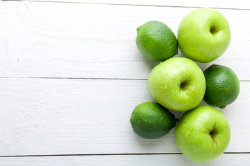 Green fruits on white wooden background. Apple, lime. Detox. Healthy food. Top view. Copy space.