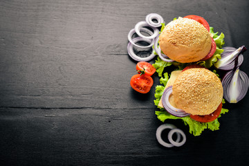Hamburger with cheese, meat, tomatoes and onions and herbs. On Wooden background. Top view. Free space.