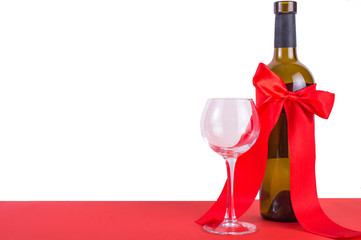A bottle of wine with a red bow and a glass. Gift concept