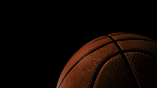Basketball ball rolling on black background