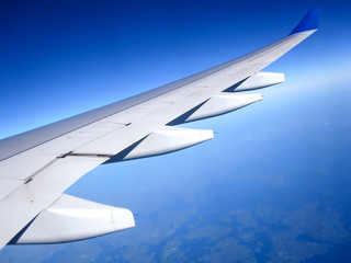 Fototapeta na wymiar Wing of the plane on blue sky background. Traveling concept. Photo applied to tourism operators