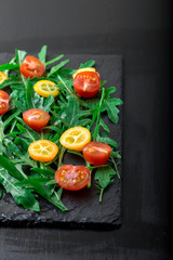 Vegetarian arugula salad with kumquat and tomato cherry on slate plate.  Healthy food. Diet