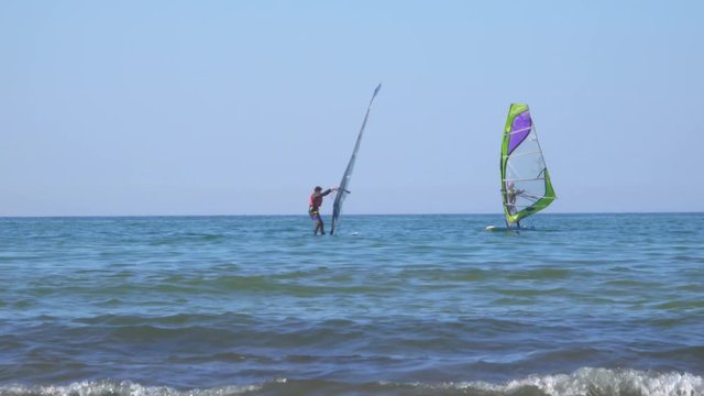 People learn windsurfing on the Baltic Sea in Zelenogradsk. In the background a dry cargo ship.