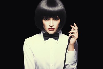 Sexy dominatrix in wig and red lips posing with whip, color graded, isolated