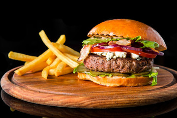 Cheeseburger with french fries on a wooden board.