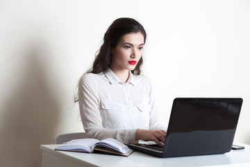 Young beautiful girl working at the computer on a white background