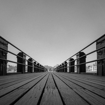 Wooden Pier. Low angle view of a wooden pier stretching out into the distance. Black and white process with added grain texture and copy space.