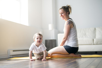 Obraz premium sports mother is engaged in fitness and yoga with a baby at home