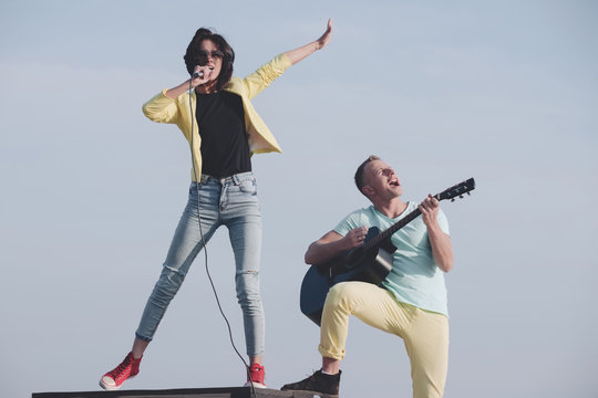 Young couple of musicians performing on idyllic blue sky
