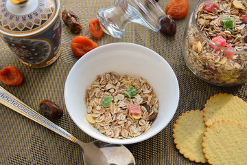 muesli in a white plate,crackers and dried fruit on a beige napkin 