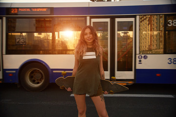 Beautiful young tattooed woman with his longboard on the road in the city in sunny weather © diignat