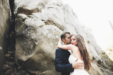 Gorgeous bride, groom kissing and hugging near the cliffs with stunning views