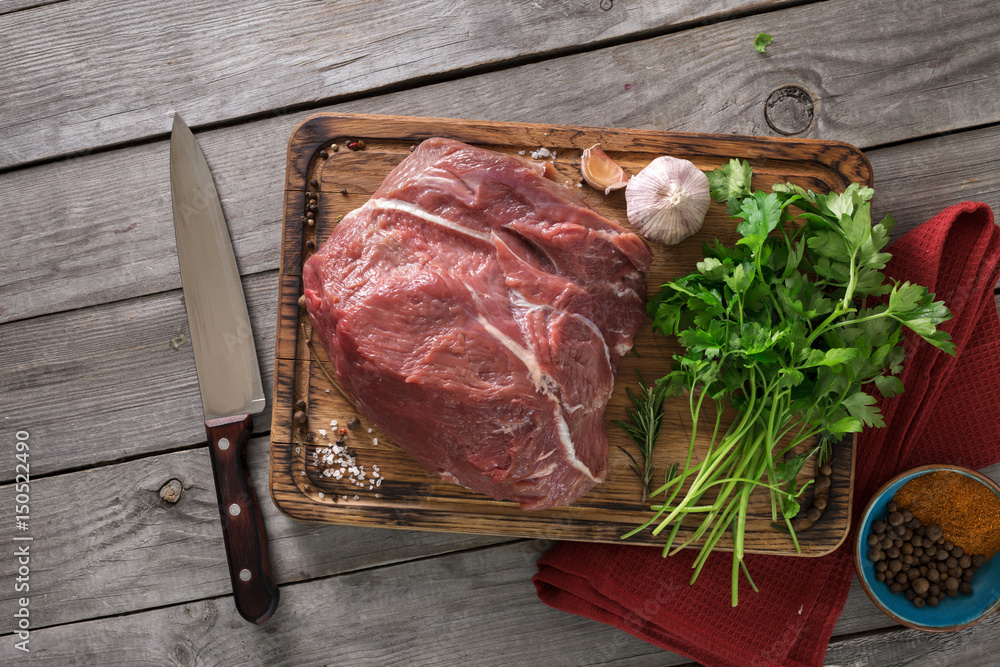 Sticker fresh beef tenderloin on cutting board with parsley and spices