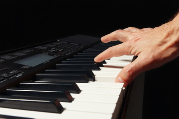Obraz premium Hand of pianist playing the electronic piano on a black background
