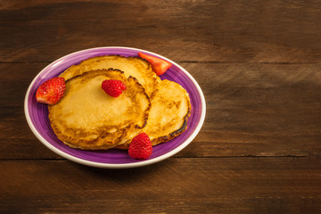 Plate of homemade pancakes with fresh fruit on dark background