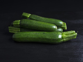 Green baby zucchinis in a pile isolated on black background