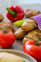 Fototapeta na wymiar Pepper, potato, kaiser bun and baguette on wood table. Vegetarian bio food concept.