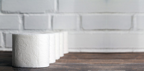 Toilet paper row on wooden table. Copy space. Selective focus. Wide panoramic image.