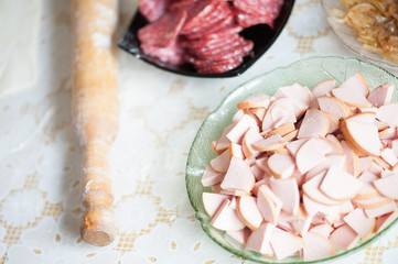 On the table the flour of the hand of the cook roll out the dough, the ingredients.