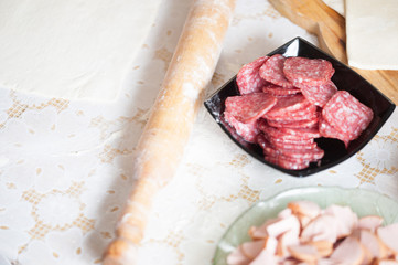 On the table the flour of the hand of the cook roll out the dough, the ingredients.