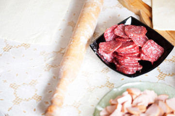On the table the flour of the hand of the cook roll out the dough, the ingredients.