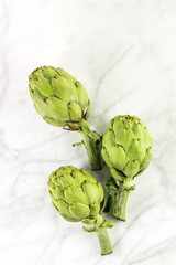 Obraz premium Artichokes on white marble texture with copyspace