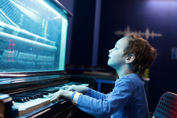 Boy playing on light music piano