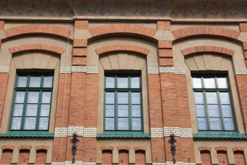 Three design green window on the facade of a brick house