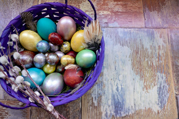 On the old wooden shabby table a dish with painted in different colors Easter eggs with feathers willow