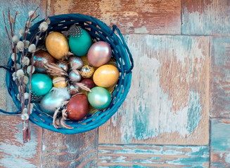 On the old wooden shabby table a dish with painted in different colors Easter eggs with feathers willow
