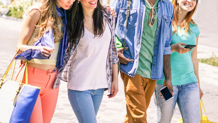 Obraz premium Happy friends walking with phones and bags in their hands on the street