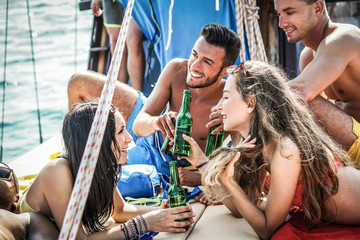 Happy friends toasting beers and chilling beers in boat vacation trip