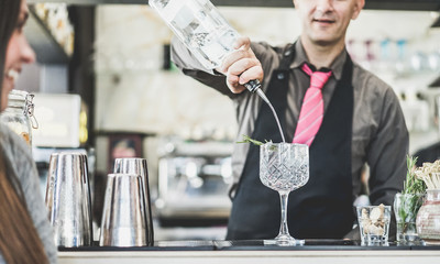Bartender mixing cocktail in a trendy crystal glass with aromatic herbs